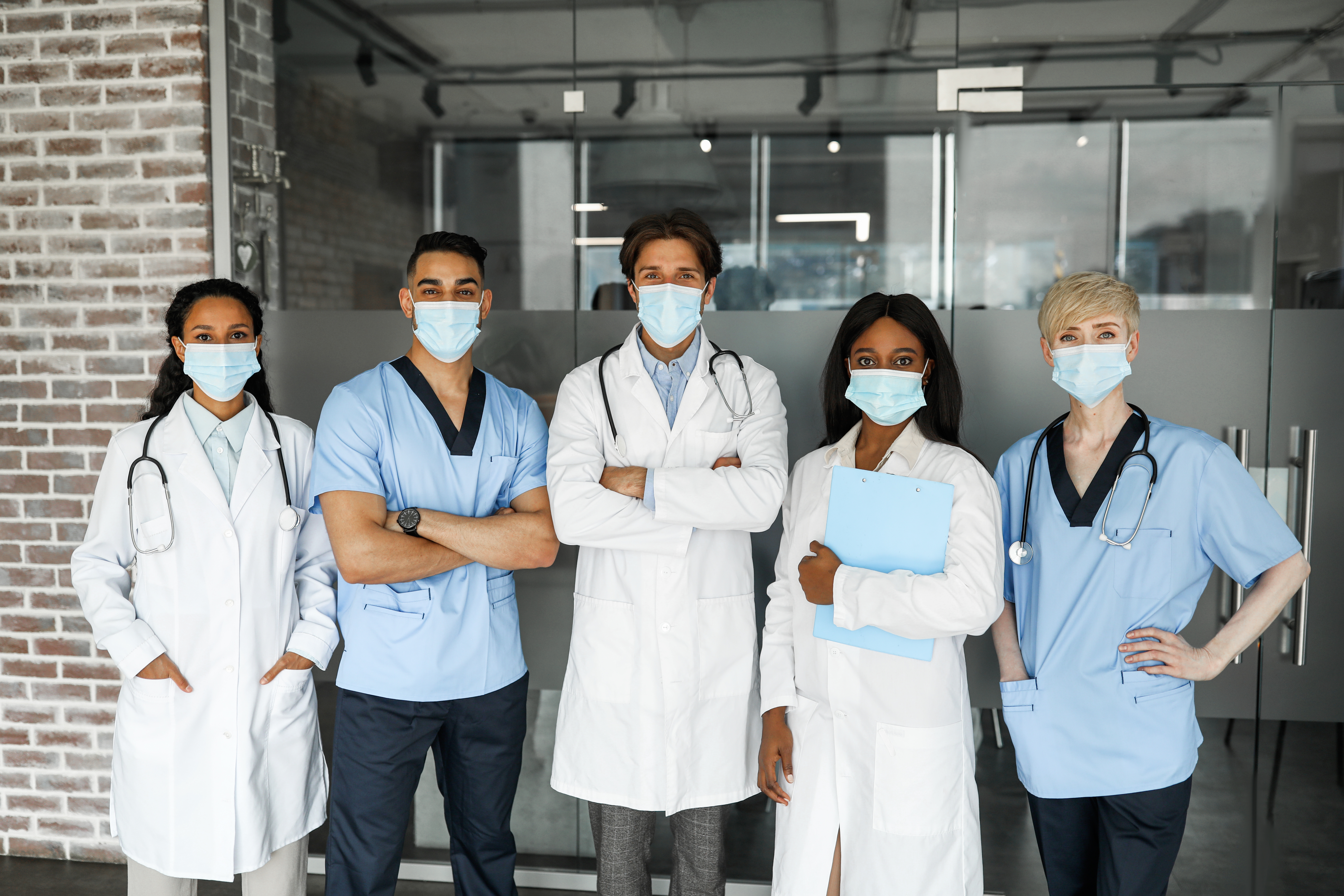 5 doctors standing with arms crossed and masks on